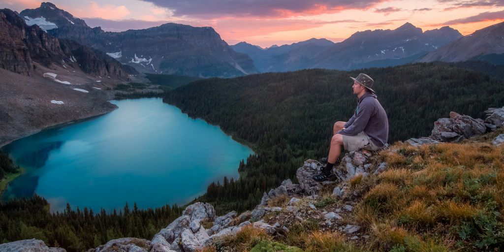 Urlaub in den Alpen - man looking on mountain sitting on rock